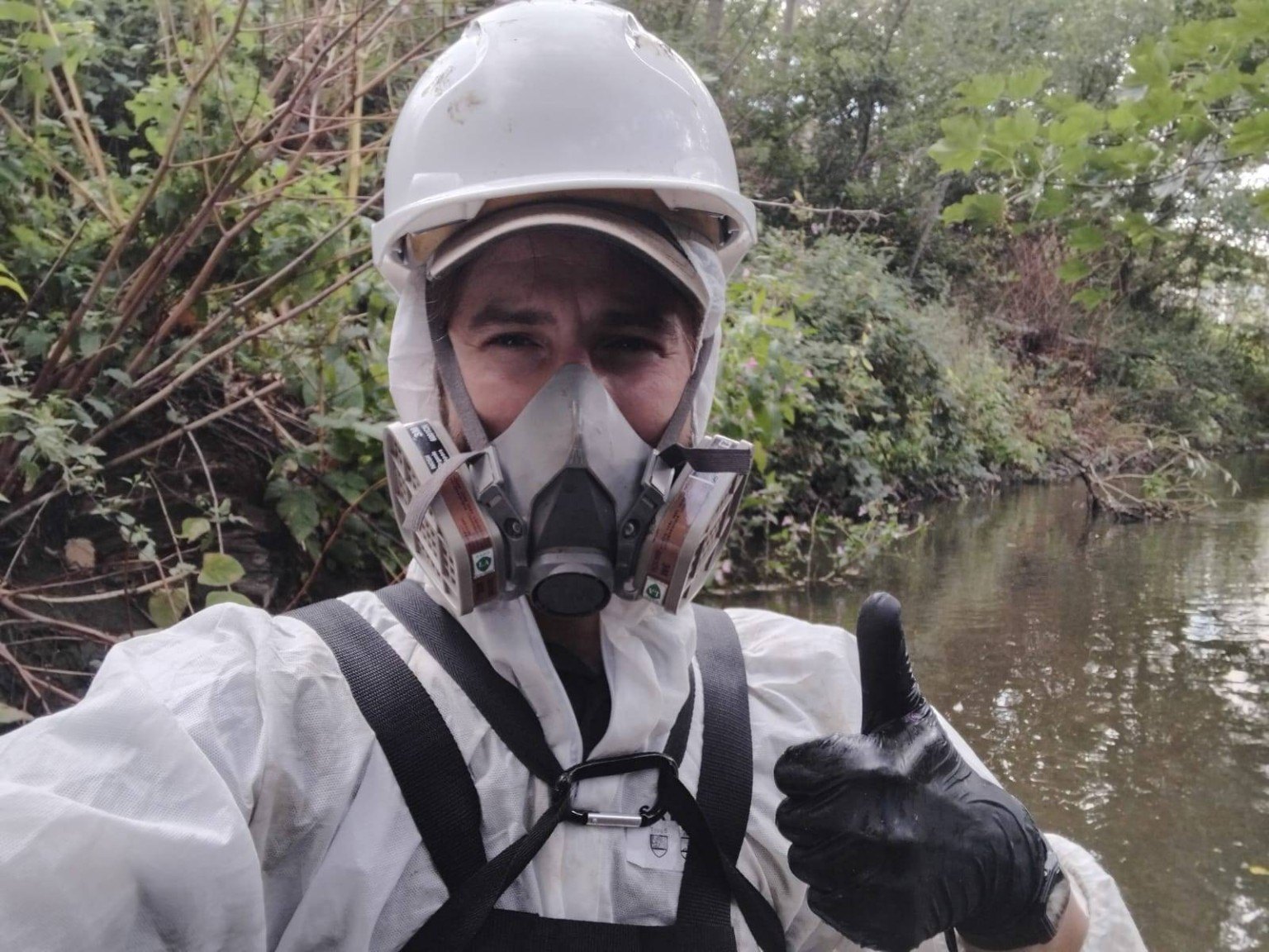 Invasive plant fieldwork beside a river while wearing protective equipment